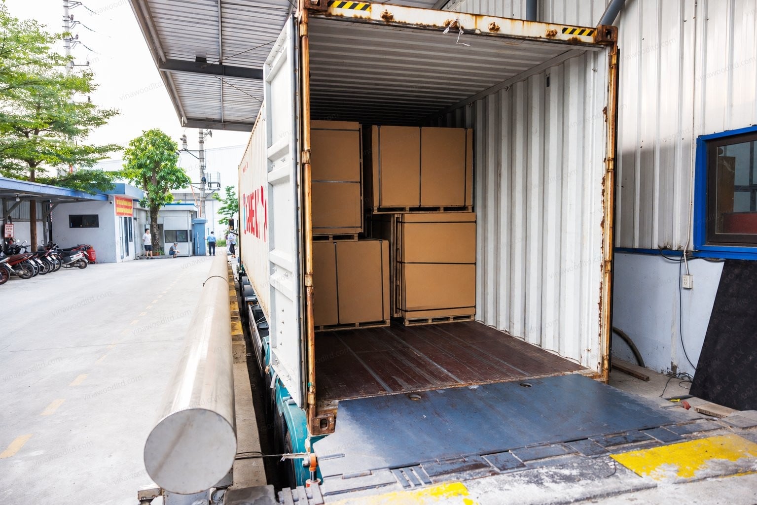 A shipping container being loaded with plywood bundles at a Vietnamese mill