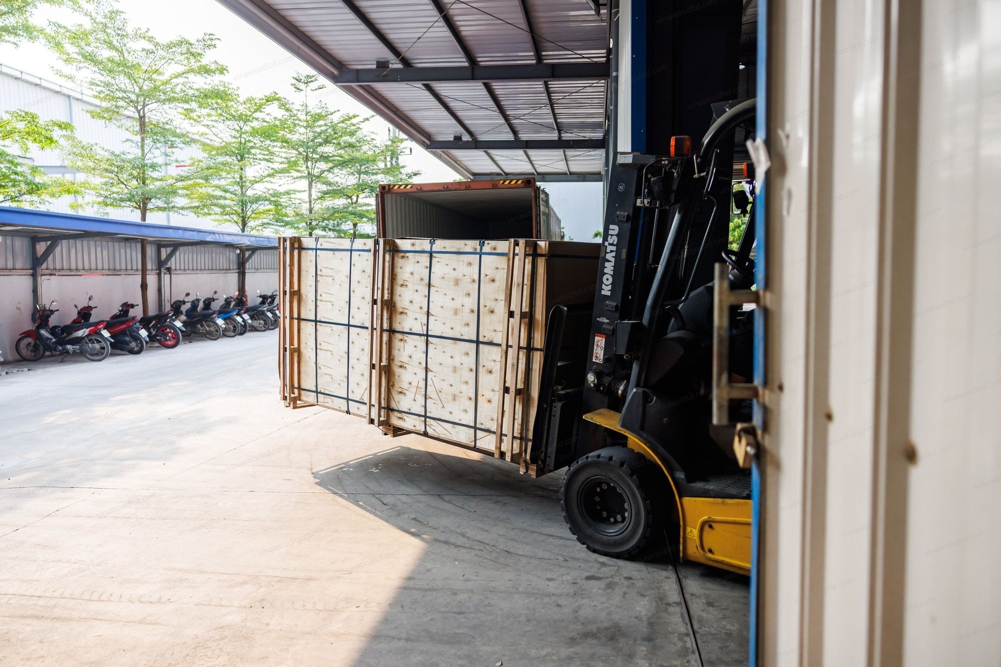 A forklift loads bundled plywood into a shipping container at a Vietnamese factory ahead of export