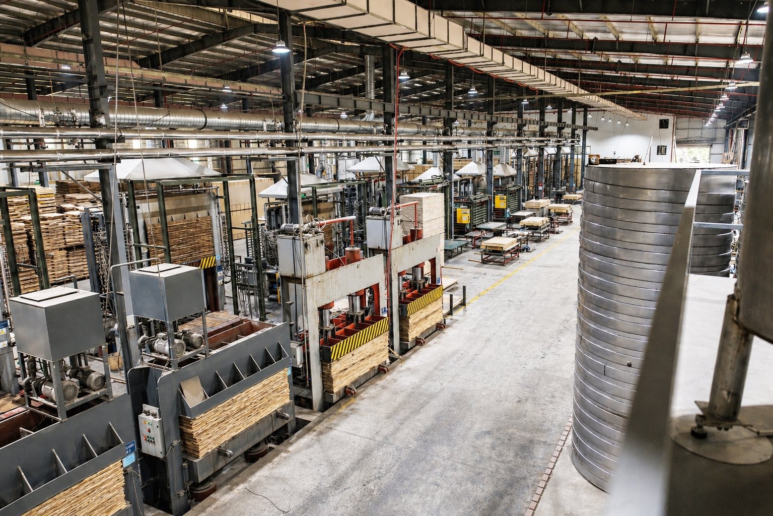 Aerial view of a Southeast Asian plywood factory production line with hot presses and stacked veneer panels.
